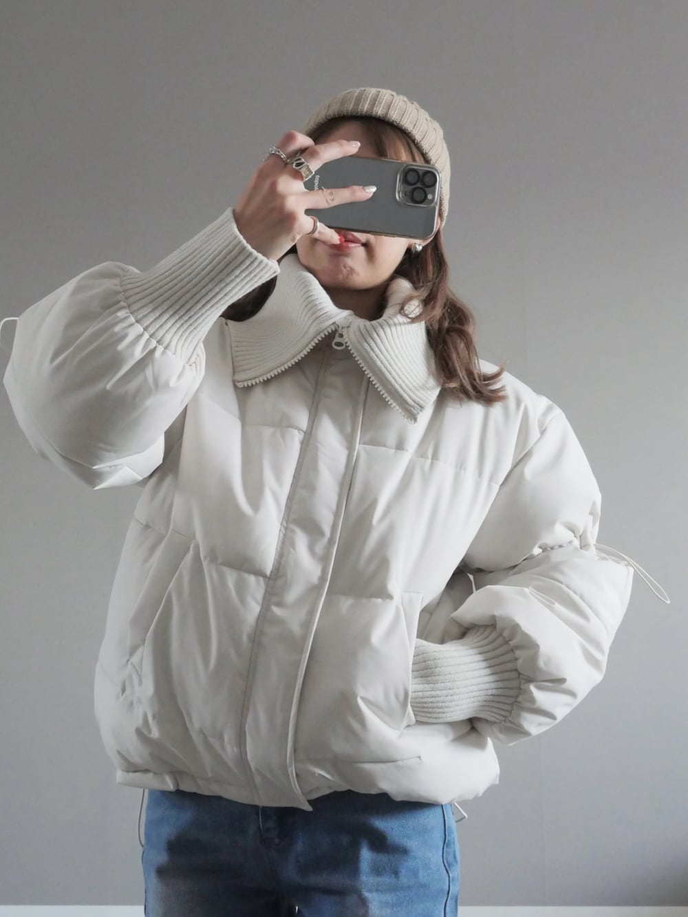 ホワイト系のダウンジャケット/コート、ブルー系のデニムパンツ、ホワイト系のショルダーバッグを着用したレディースの冬コーディネートの2枚目の写真