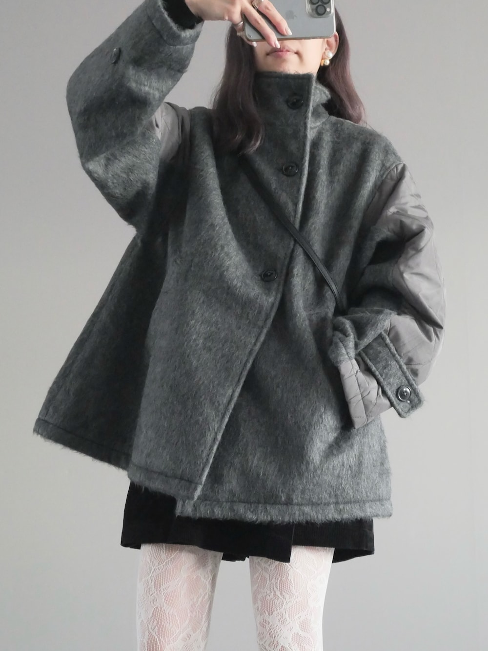 グレー系のステンカラーコート、ブラック系のパンツ、ブラック系のブーツを着用したレディースの秋コーディネートの2枚目の写真