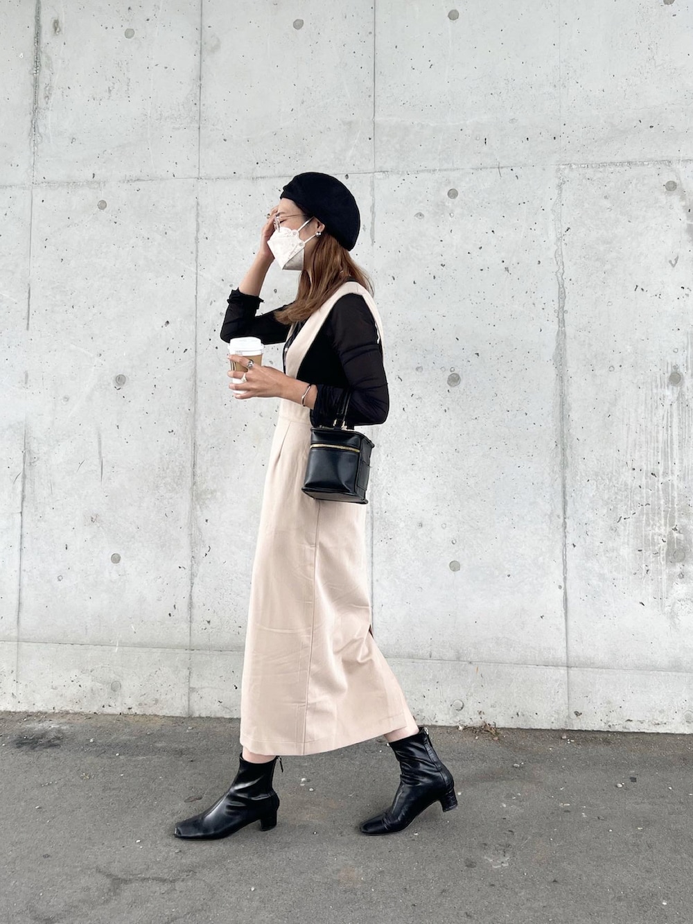 ベージュ系のジャンパースカート、ブラック系のトップス、ブラック系のショルダーバッグを着用したレディースの秋コーディネートの2枚目の写真