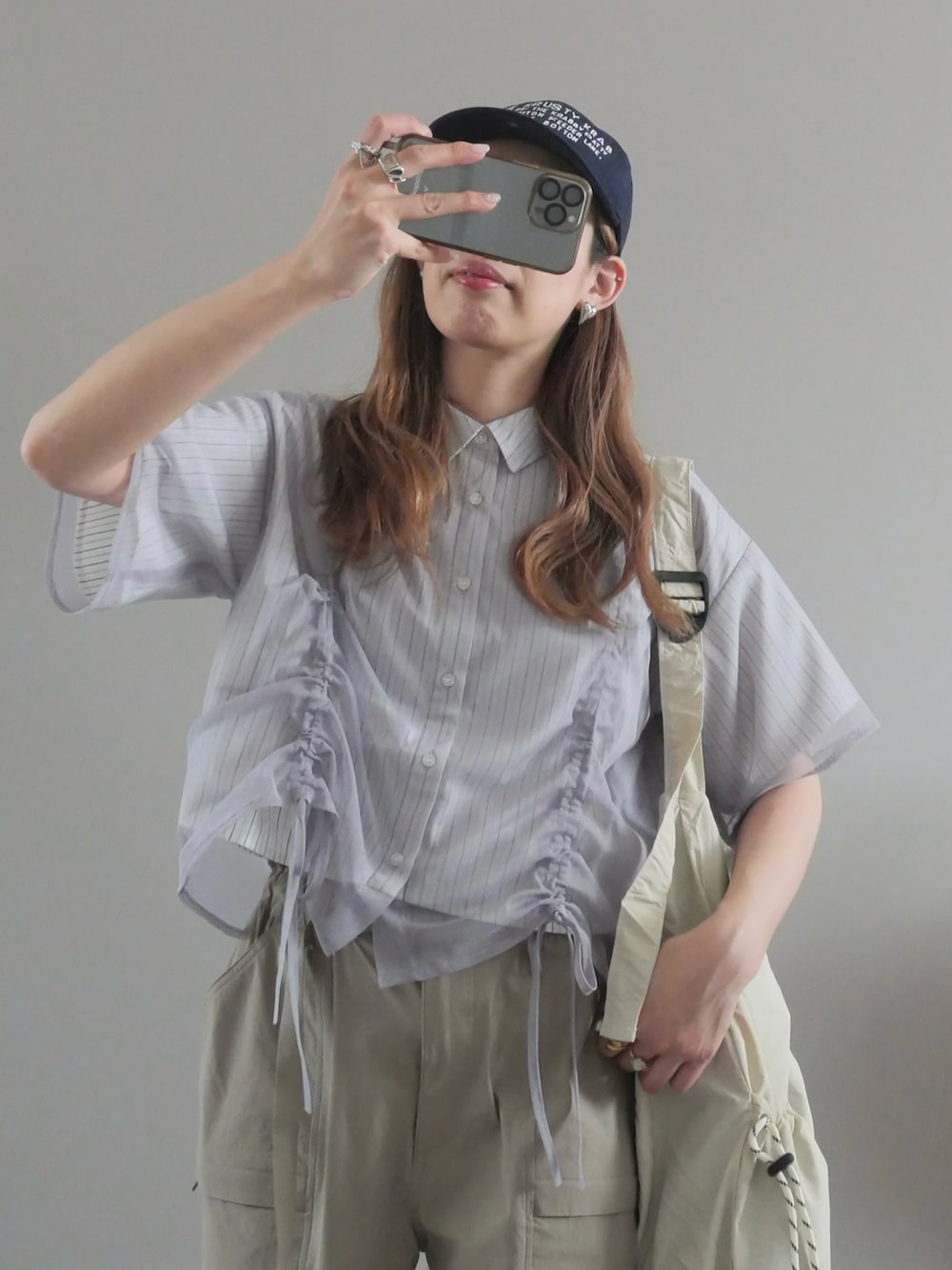 グレー系のシャツ/ブラウス、ホワイト系のメッセンジャーバッグ、ベージュ系のパンツを着用したレディースの春コーディネートの2枚目の写真