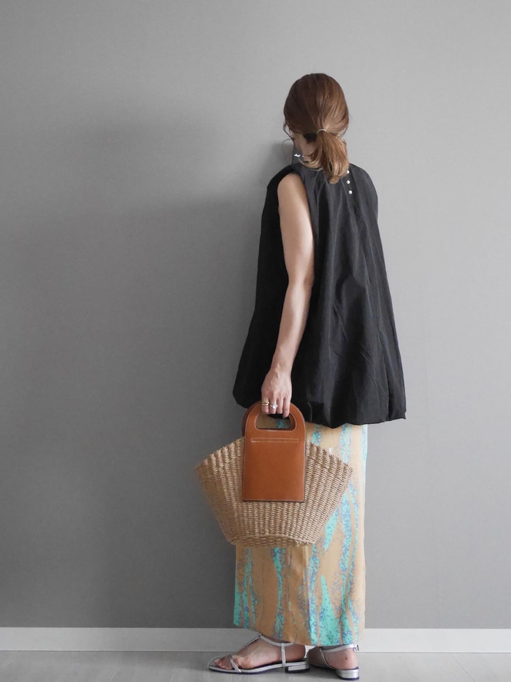 ブラック系のシャツ/ブラウス、オレンジ系のスカート、ブラウン系のかごバッグを着用したレディースの夏コーディネートの2枚目の写真