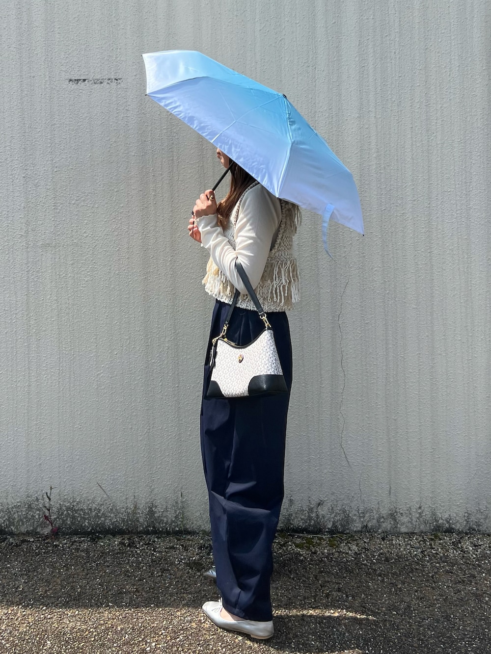 ホワイト系のベスト、ブラック系のショルダーバッグ、ブルー系のその他パンツを着用したレディースの春コーディネートの2枚目の写真