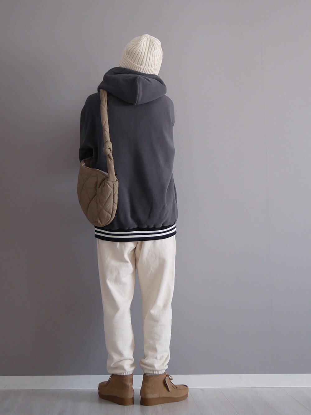 グレー系のパーカー、ホワイト系のパンツ、ブラウン系のメッセンジャーバッグを着用したレディースの秋コーディネートの3枚目の写真