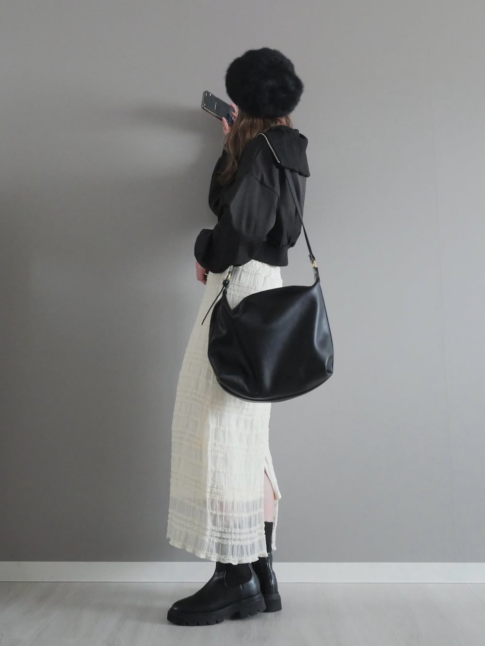 ブラック系のセットアップ、ホワイト系のスカート、ブラック系のショルダーバッグを着用したレディースの冬コーディネートの3枚目の写真