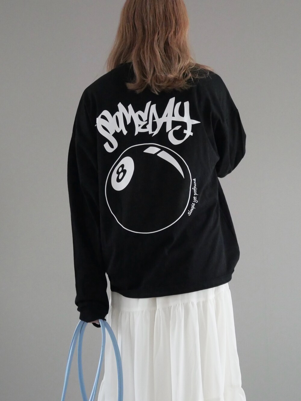 ブラック系のTシャツ/カットソー、ホワイト系のスカート、ブラック系のブーツを着用したレディースの秋コーディネートの2枚目の写真