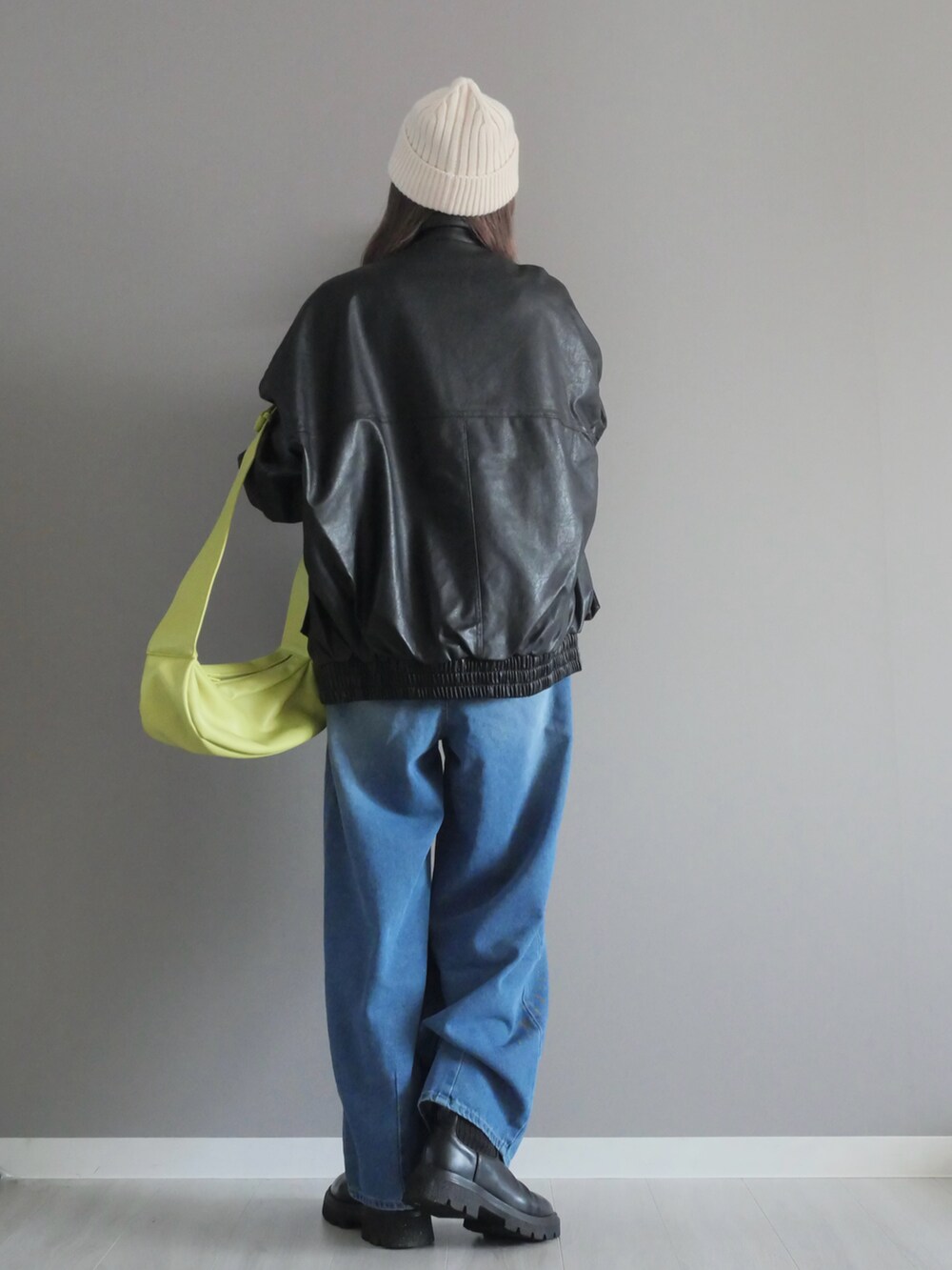 ブラック系のブルゾン、ホワイト系のTシャツ/カットソー、ブルー系のデニムパンツを着用したレディースの冬コーディネートの3枚目の写真