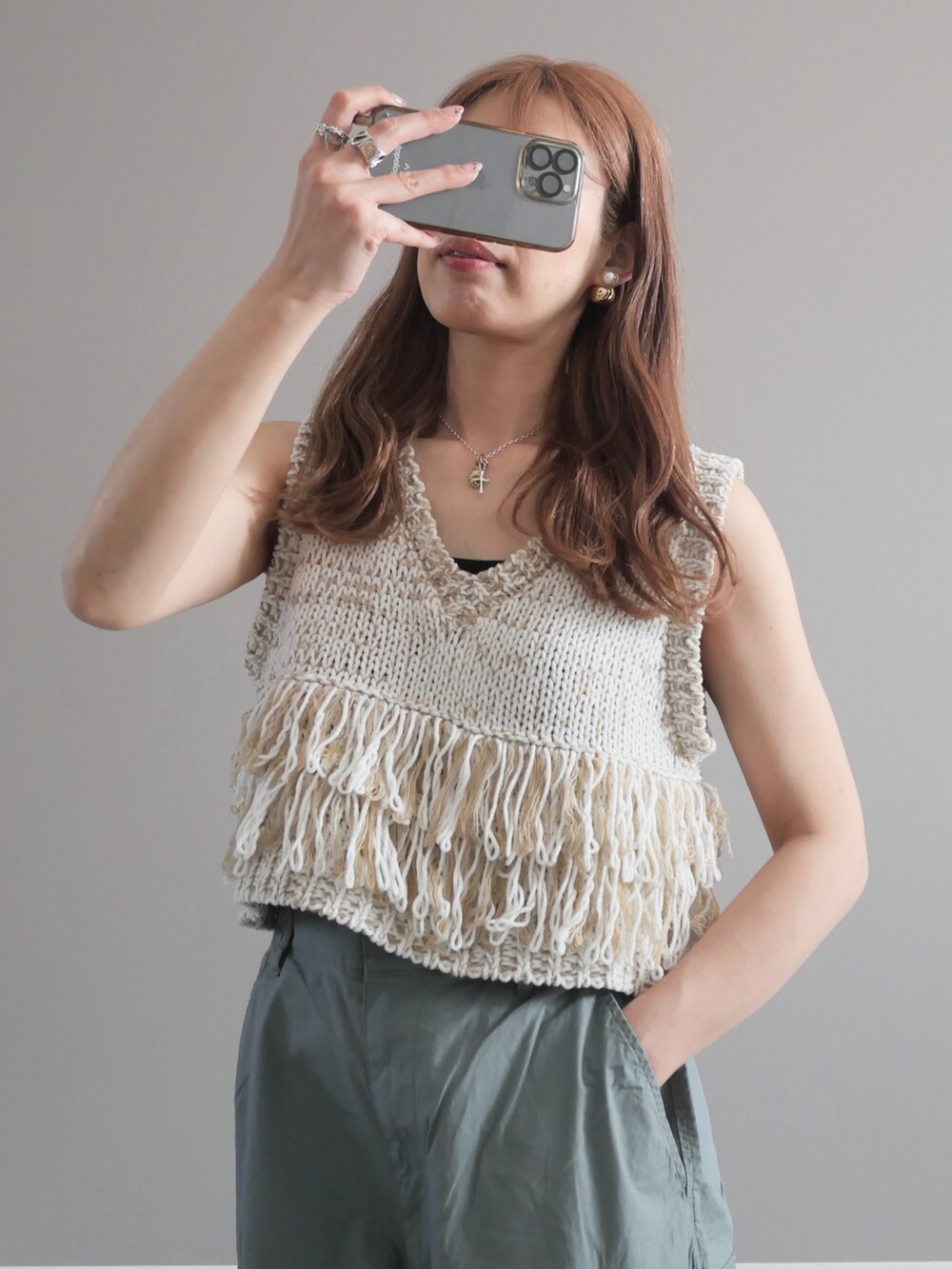 ホワイト系のベスト、グリーン系のパンツ、ブラック系のショルダーバッグを着用したレディースの春コーディネートの2枚目の写真