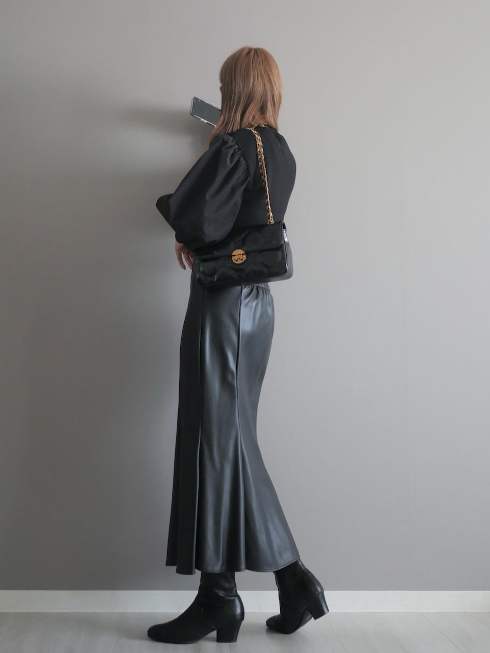 ブラック系のニット/セーター、ブラック系のショルダーバッグ、ブラック系のスカートを着用したレディースの秋コーディネートの4枚目の写真