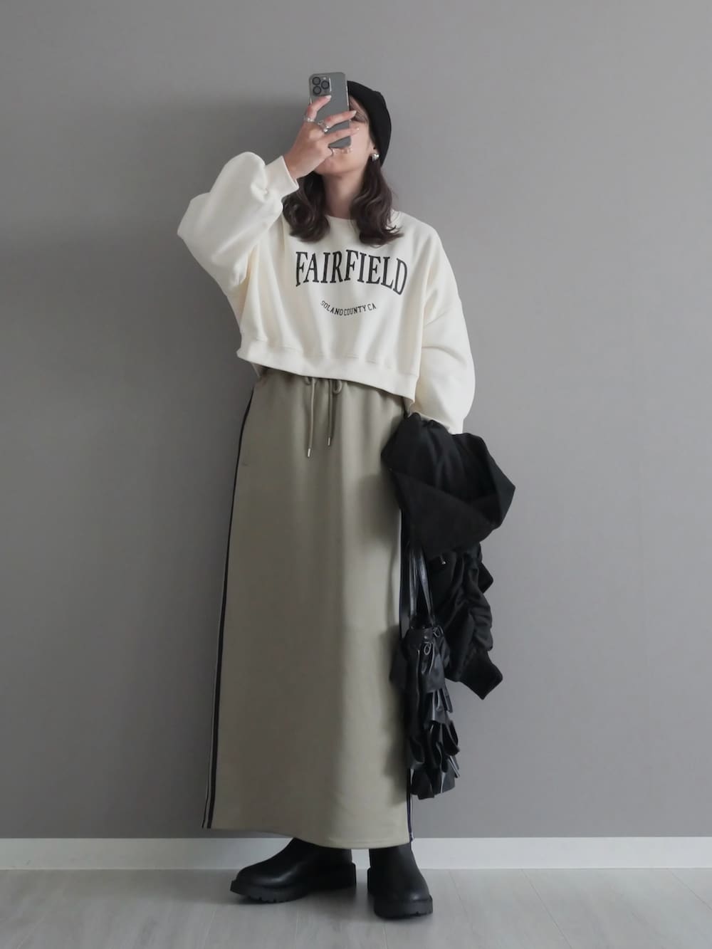 ホワイト系のスウェット、ブラック系のブルゾン、ブルー系のスカートを着用したレディースの秋コーディネートの3枚目の写真