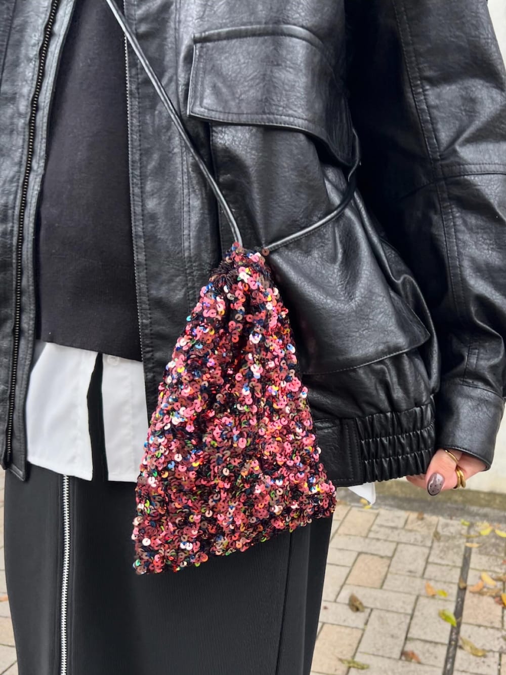 レッド系のショルダーバッグ、ブラック系のトップス、ホワイト系のシャツ/ブラウスを着用したレディースの冬コーディネートの2枚目の写真