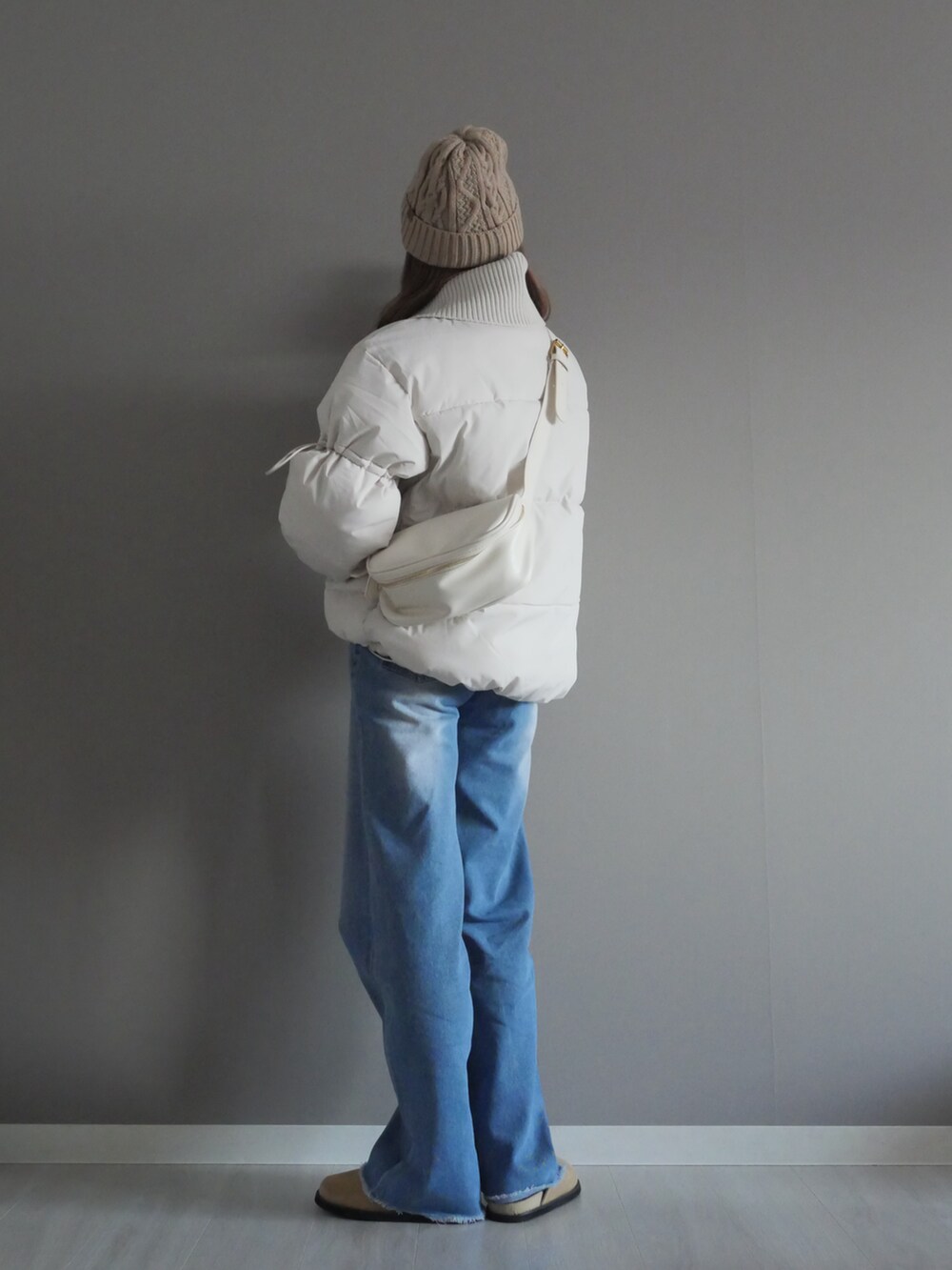 ホワイト系のダウンジャケット/コート、ブルー系のデニムパンツ、ホワイト系のショルダーバッグを着用したレディースの冬コーディネートの5枚目の写真