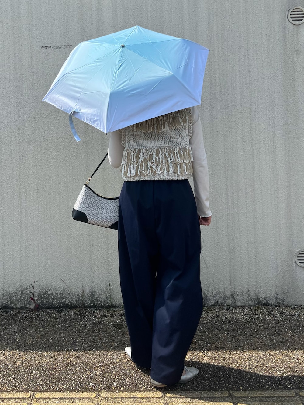 ホワイト系のベスト、ブラック系のショルダーバッグ、ブルー系のその他パンツを着用したレディースの春コーディネートの3枚目の写真