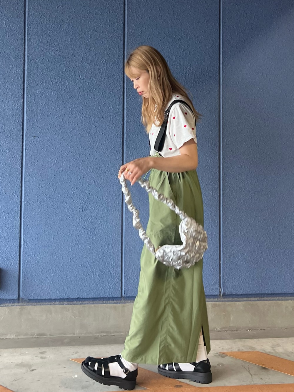 グリーン系のジャンパースカート、ベージュ系のTシャツ/カットソー、シルバー系のハンドバッグを着用したレディースの夏コーディネートの3枚目の写真