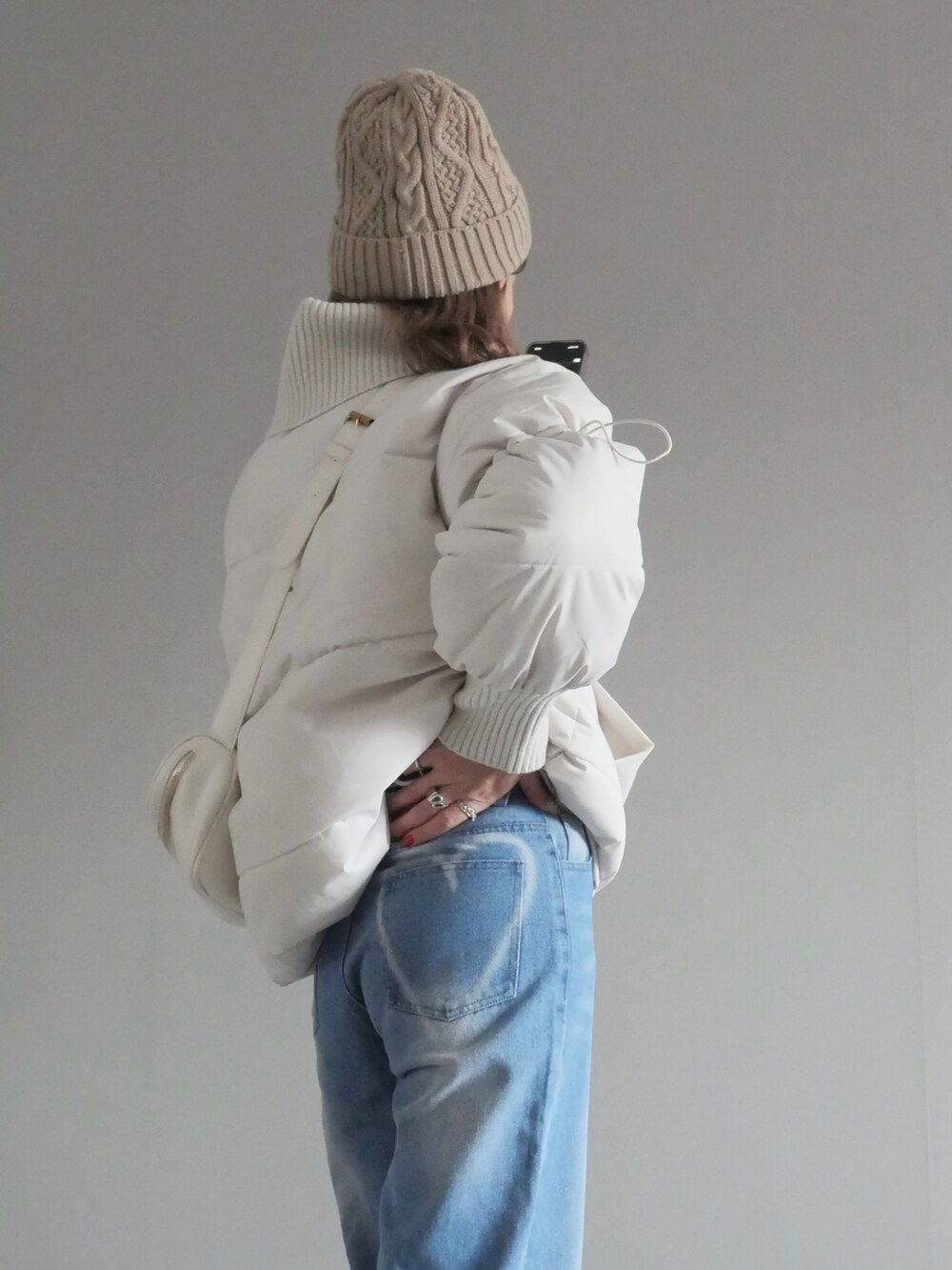 ホワイト系のダウンジャケット/コート、ブルー系のデニムパンツ、ホワイト系のショルダーバッグを着用したレディースの冬コーディネートの4枚目の写真