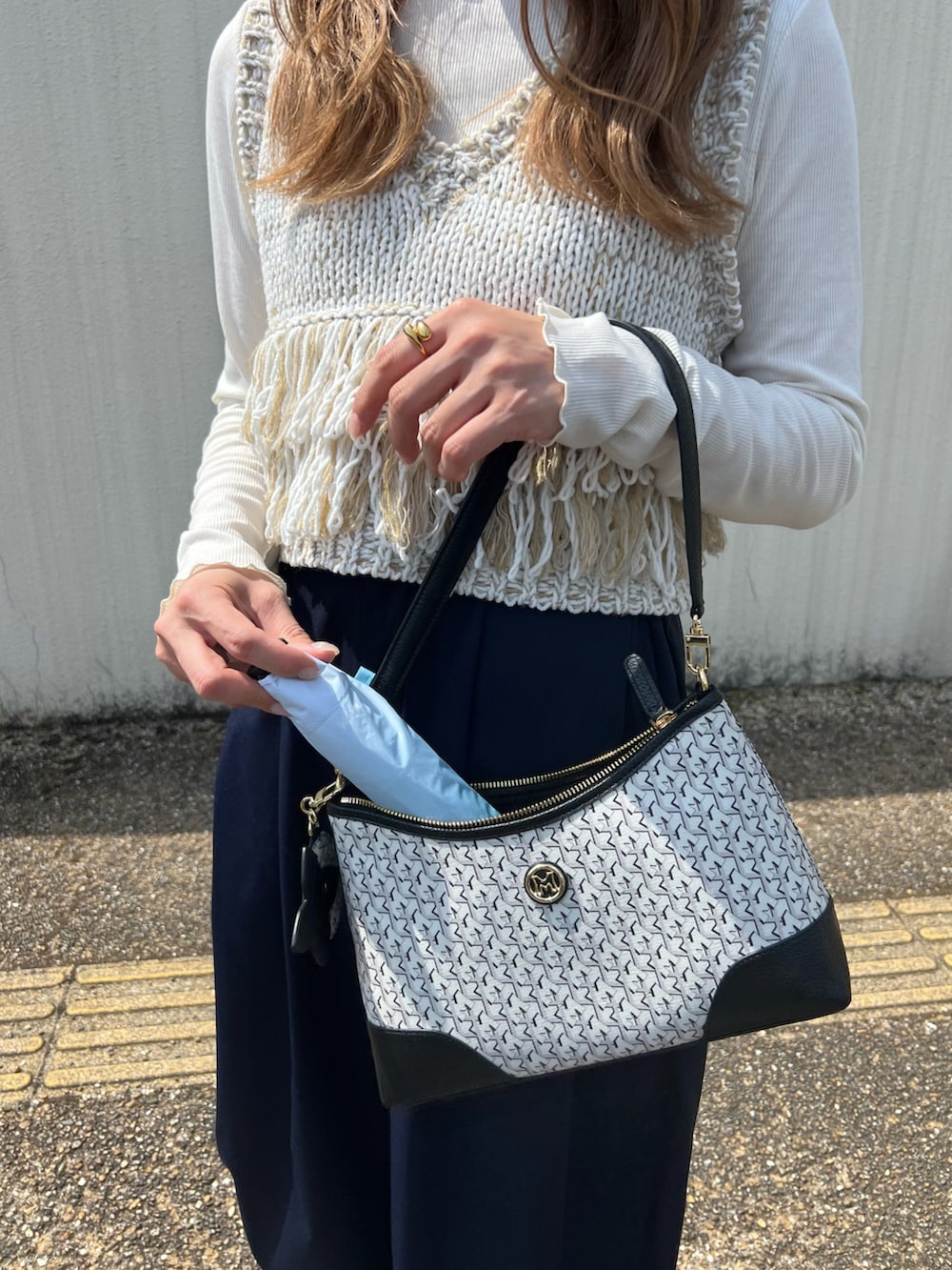 ホワイト系のベスト、ブラック系のショルダーバッグ、ブルー系のその他パンツを着用したレディースの春コーディネートの4枚目の写真