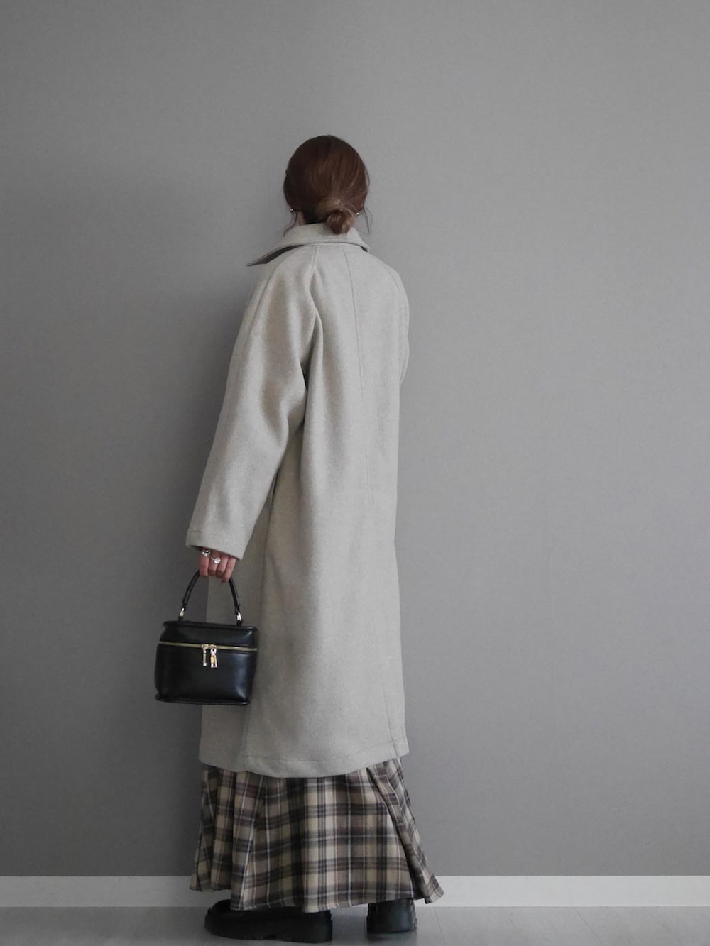 ベージュ系のステンカラーコート、レッド系のカーディガン/ボレロ、ベージュ系のスカートを着用したレディースの秋コーディネートの3枚目の写真