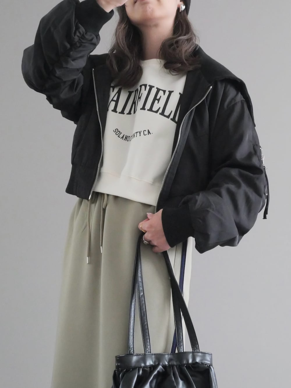 ホワイト系のスウェット、ブラック系のブルゾン、ブルー系のスカートを着用したレディースの秋コーディネートの2枚目の写真