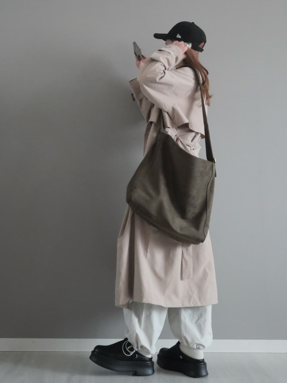 ベージュ系のトレンチコート、グリーン系のショルダーバッグ、ブラック系のスリッポンを着用したレディースの春コーディネートの4枚目の写真