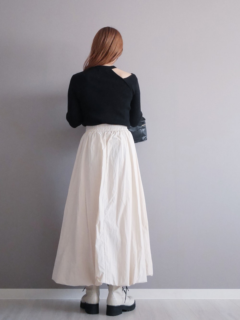 ブラック系のニット/セーター、ホワイト系のスカート、ホワイト系のブーツを着用したレディースの秋コーディネートの3枚目の写真
