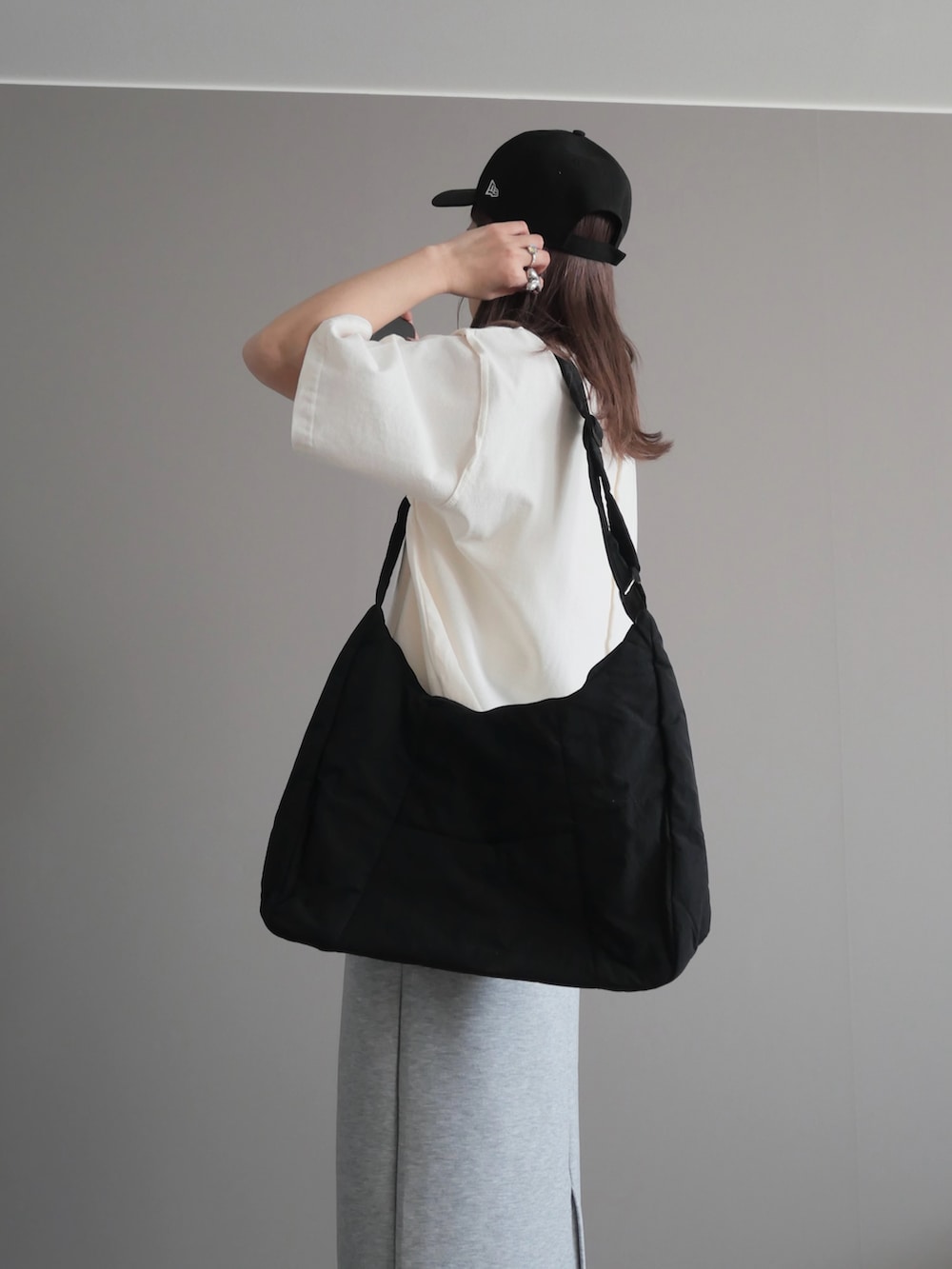 ブラック系のショルダーバッグ、ブラック系のスニーカー、シルバー系のネックレスを着用したレディースの春コーディネートの3枚目の写真