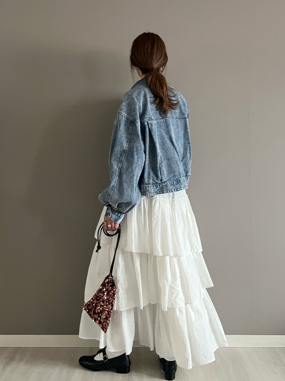 ブルー系のデニムジャケット、グレー系のTシャツ/カットソー、ホワイト系のスカートを着用したレディースの春コーディネートの4枚目の写真