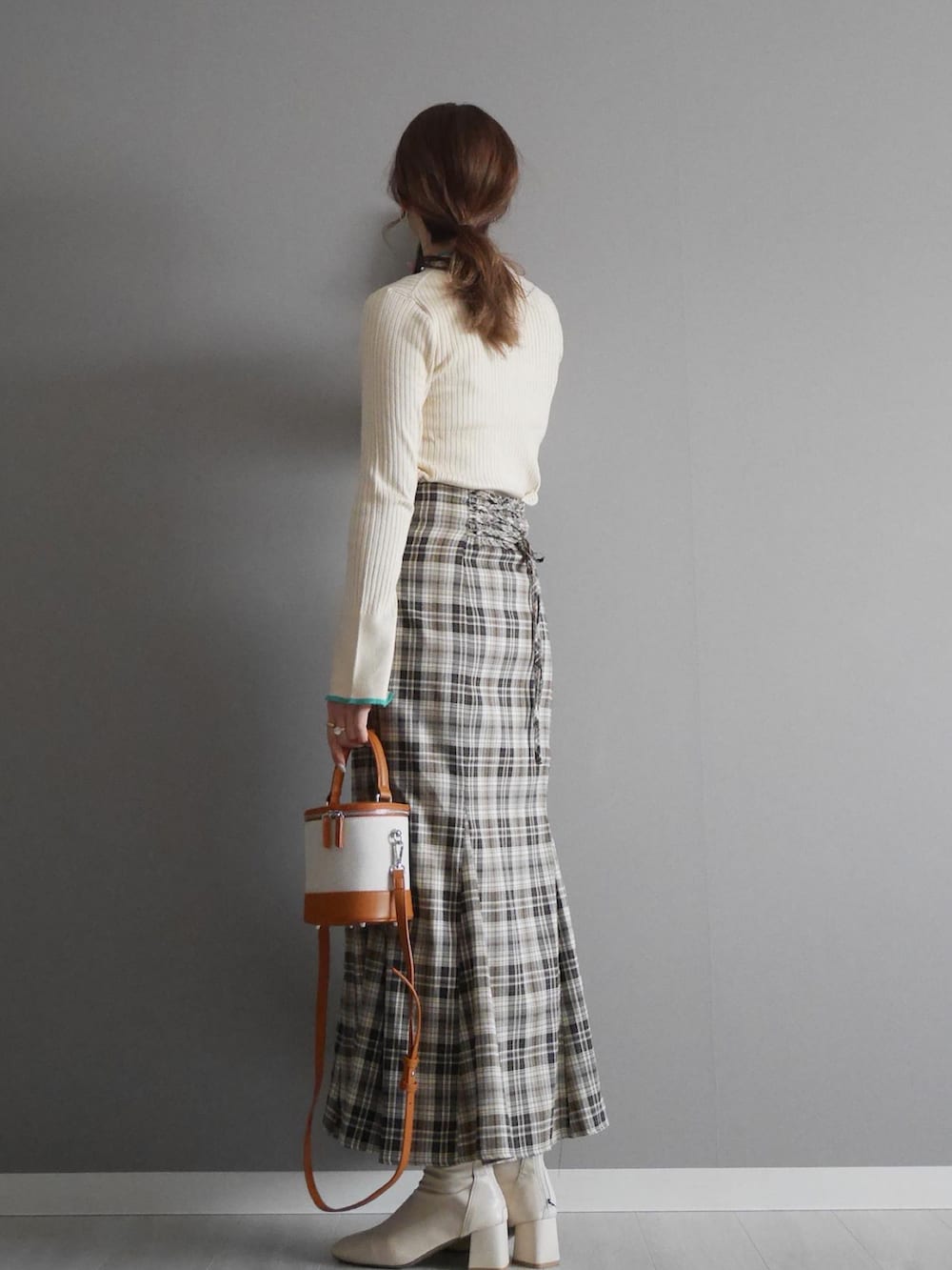 ホワイト系のニット/セーター、ベージュ系のスカート、イエロー系のショルダーバッグを着用したレディースの冬コーディネートの2枚目の写真