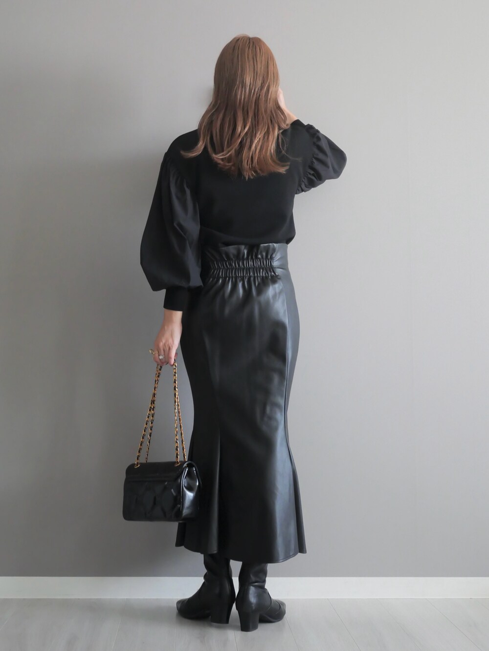 ブラック系のニット/セーター、ブラック系のショルダーバッグ、ブラック系のスカートを着用したレディースの秋コーディネートの5枚目の写真