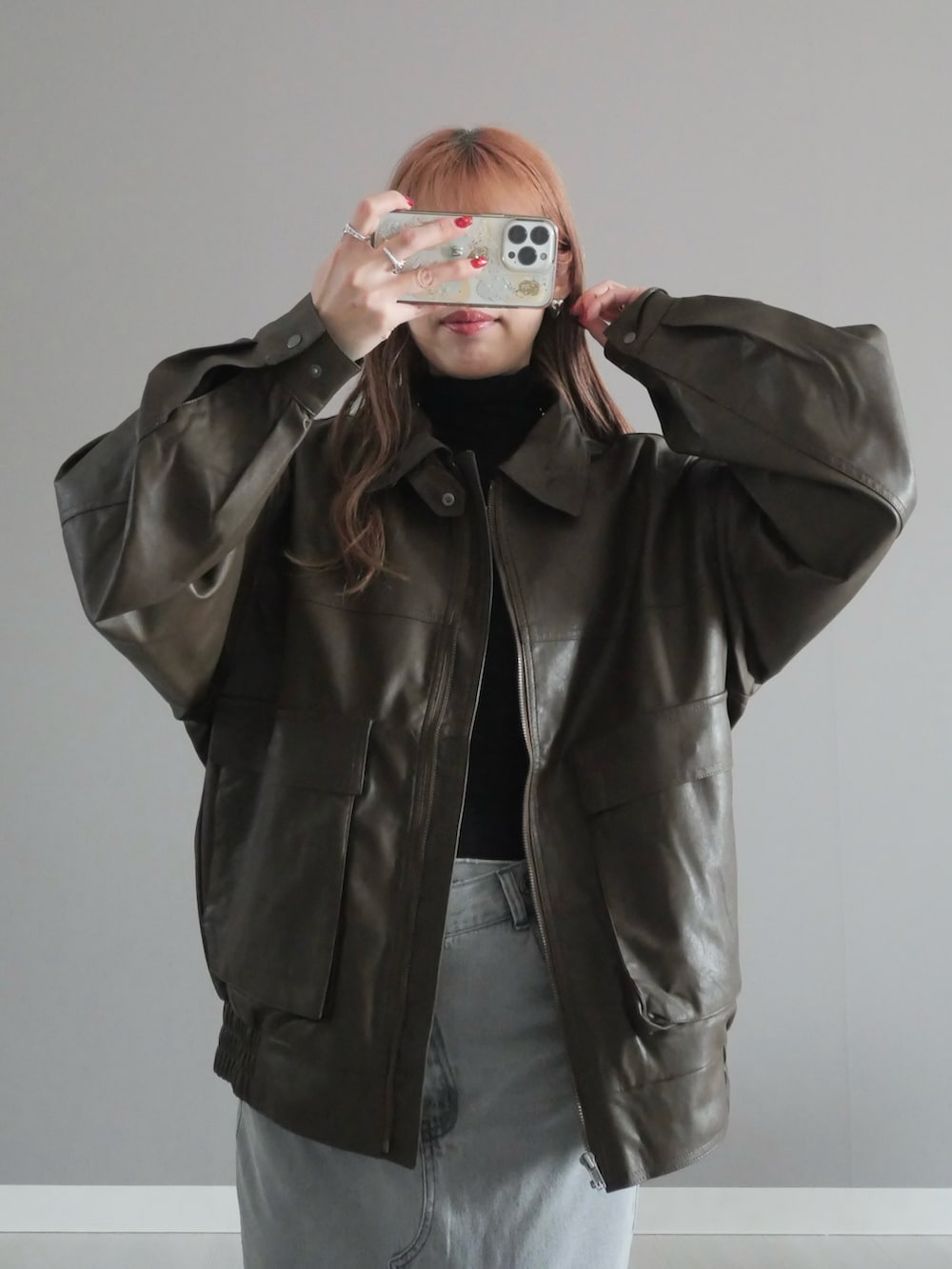 グレー系のデニムスカート、ブラック系のトートバッグ、ブラウン系のブルゾンを着用したレディースの冬コーディネートの2枚目の写真