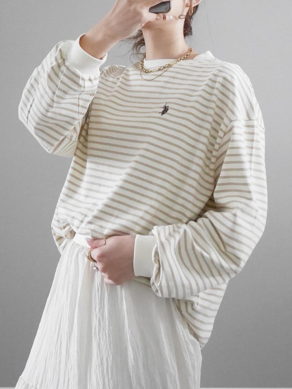 ベージュ系のTシャツ/カットソー、ホワイト系のスカート、ブラック系のショルダーバッグを着用したレディースの冬コーディネートの2枚目の写真