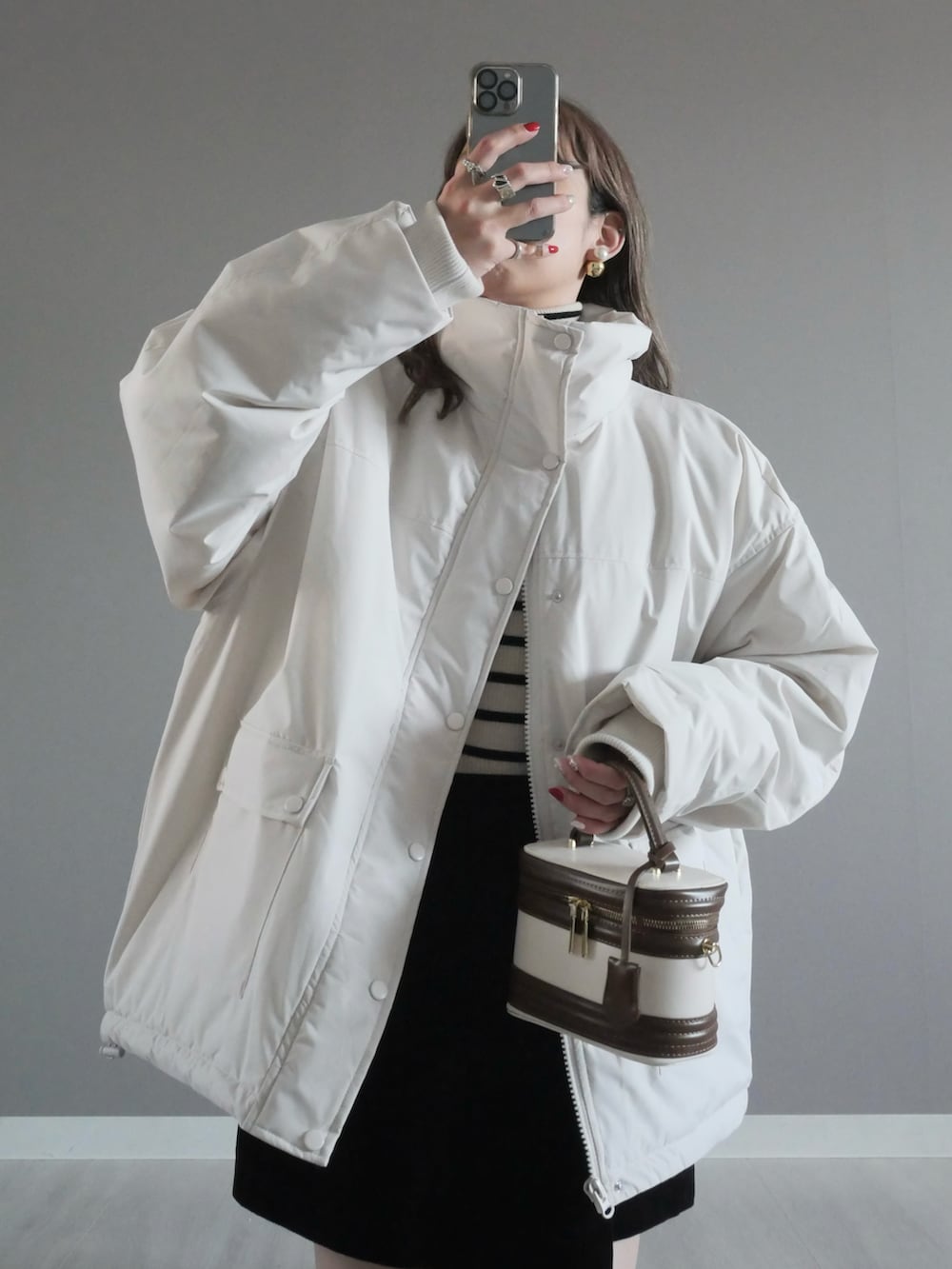 ホワイト系のブルゾン、ブラック系のパンツ、ホワイト系のハンドバッグを着用したレディースの冬コーディネートの2枚目の写真