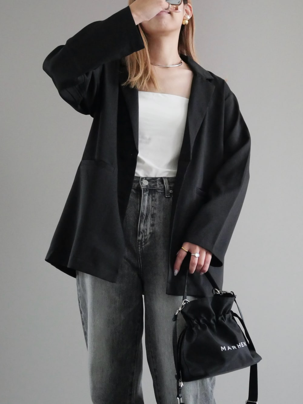 ブラック系のテーラードジャケット、グレー系のデニムパンツ、ブラック系のバッグを着用したレディースの夏コーディネートの2枚目の写真