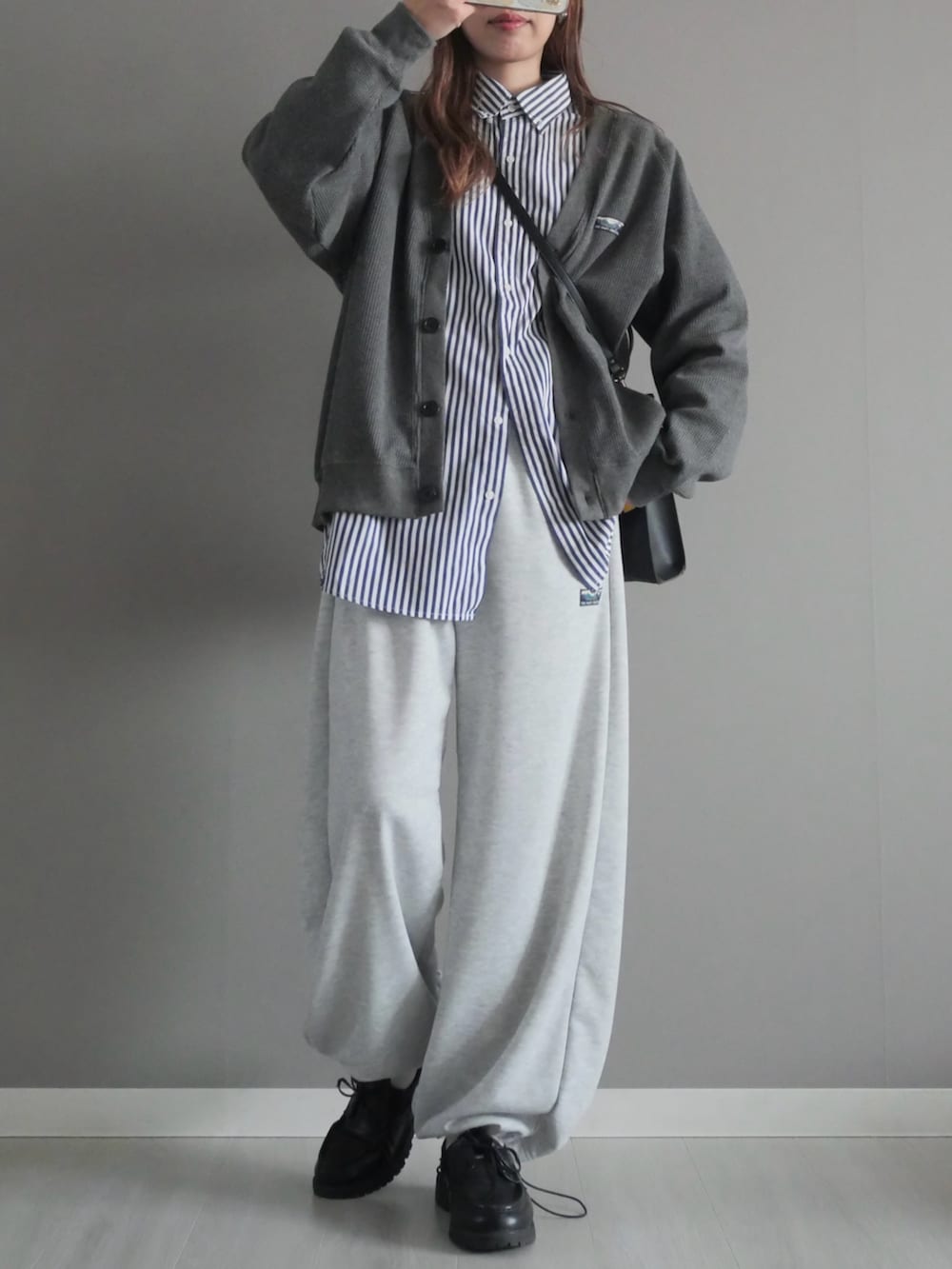グレー系のカーディガン/ボレロ、グレー系のスウェットパンツ、ブラック系のショルダーバッグを着用したレディースの冬コーディネートの3枚目の写真