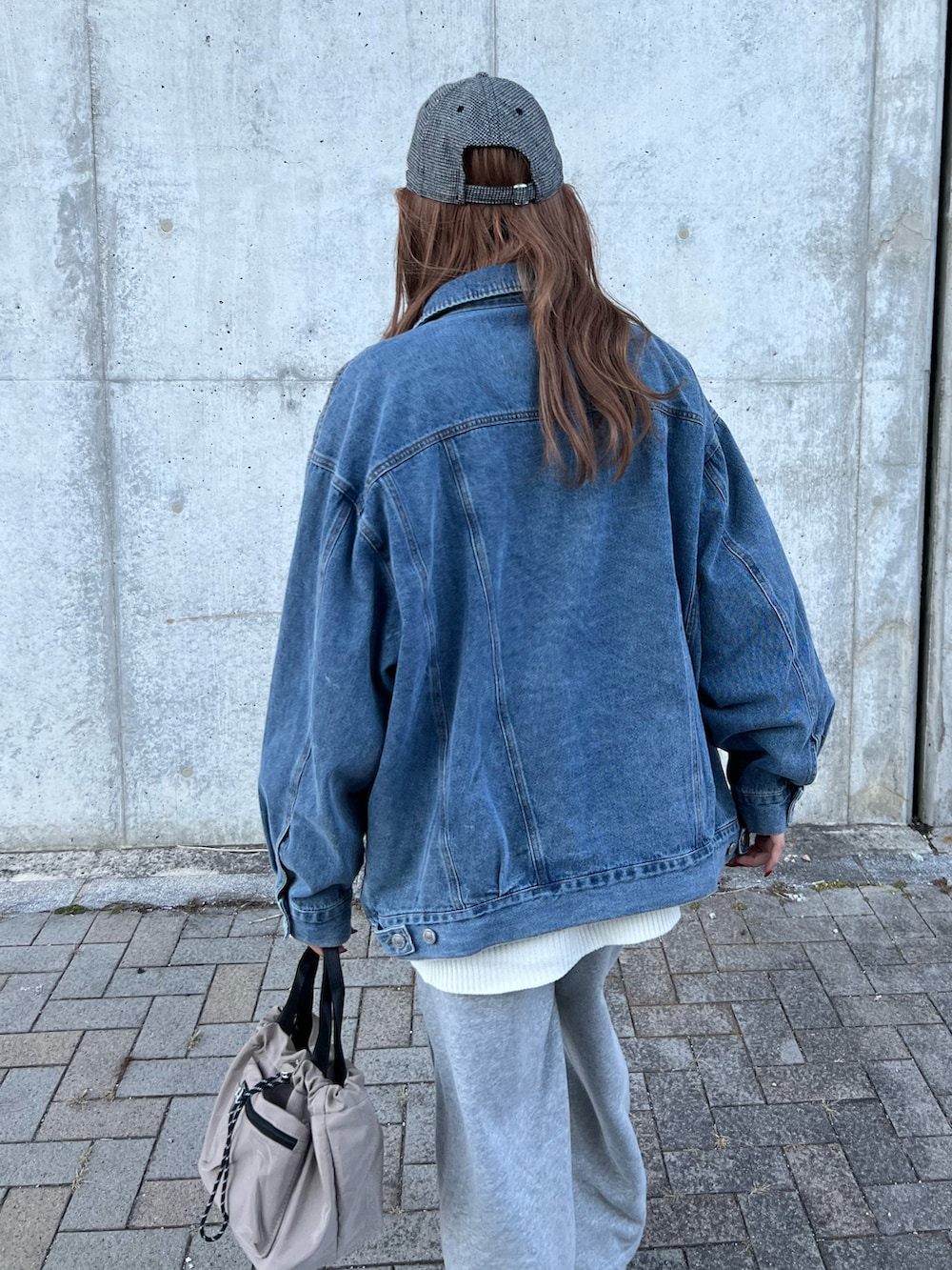 ブルー系のデニムジャケット、ホワイト系のニット/セーター、グレー系のスウェットパンツを着用したレディースの春コーディネートの4枚目の写真