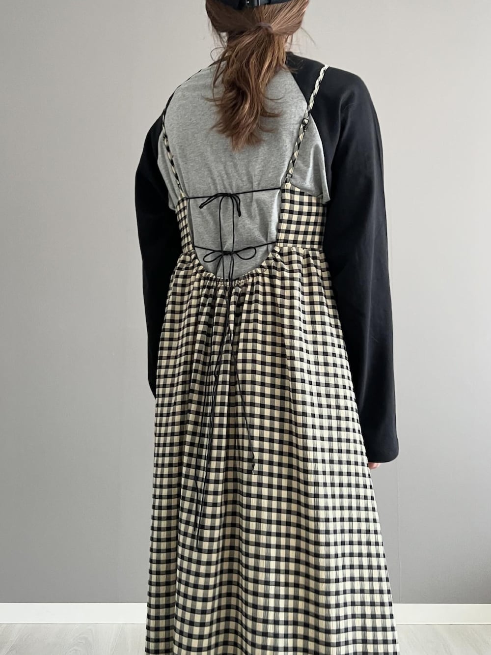 ブラック系のワンピース、グレー系のTシャツ/カットソー、ブラック系のショルダーバッグを着用したレディースの春コーディネートの2枚目の写真