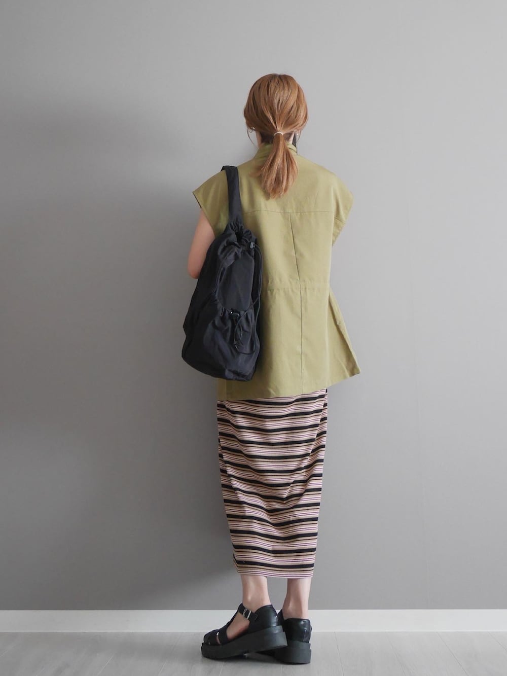 グリーン系のベスト、ブラック系のワンピース、ブラック系のショルダーバッグを着用したレディースの夏コーディネートの2枚目の写真