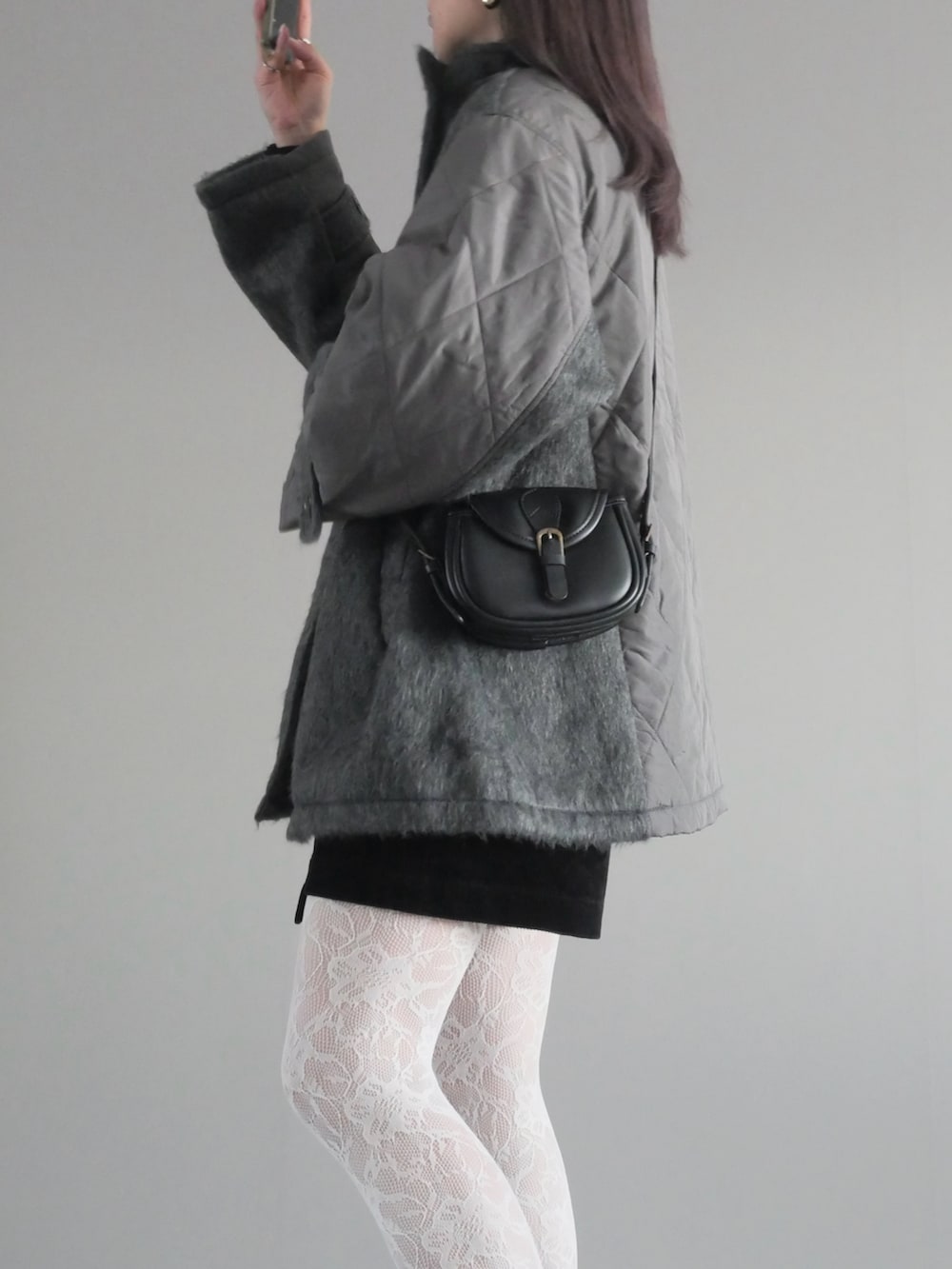 グレー系のステンカラーコート、ブラック系のパンツ、ブラック系のブーツを着用したレディースの秋コーディネートの4枚目の写真