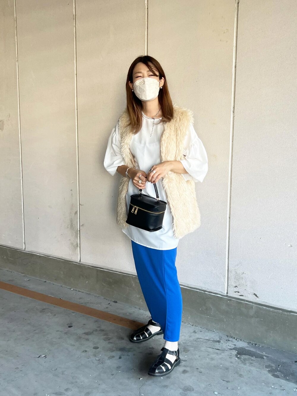 ホワイト系のベスト、ブラック系のショルダーバッグ、ブラック系のサンダルを着用したレディースの夏コーディネートの2枚目の写真