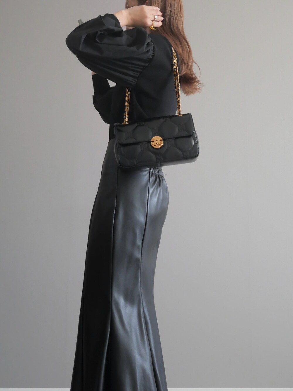 ブラック系のニット/セーター、ブラック系のショルダーバッグ、ブラック系のスカートを着用したレディースの秋コーディネートの3枚目の写真