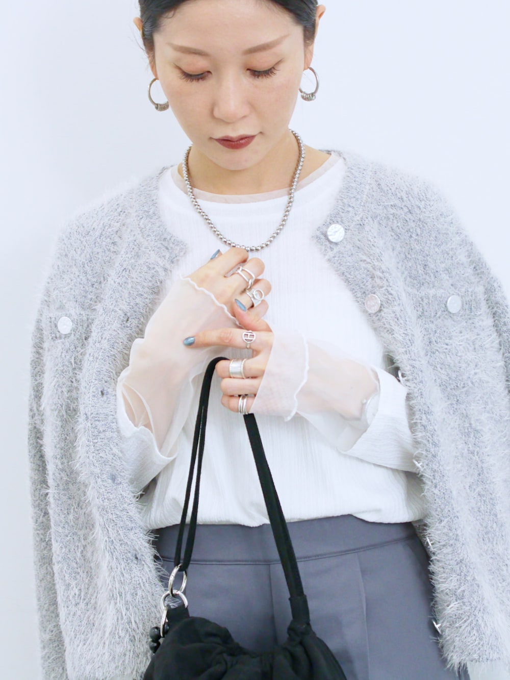 ブラック系のハンドバッグ、ブラック系のドレスシューズ、ホワイト系のTシャツ/カットソーを着用したレディースの冬コーディネートの2枚目の写真