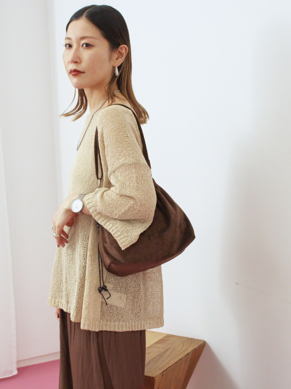 ベージュ系のニット/セーター、ブラウン系のその他パンツ、ブラウン系のハンドバッグを着用したレディースの秋コーディネートの3枚目の写真