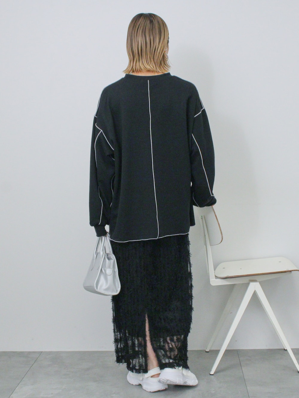 ブラック系のTシャツ/カットソー、シルバー系のハンドバッグ、ホワイト系のドレスシューズを着用したレディースの冬コーディネートの3枚目の写真