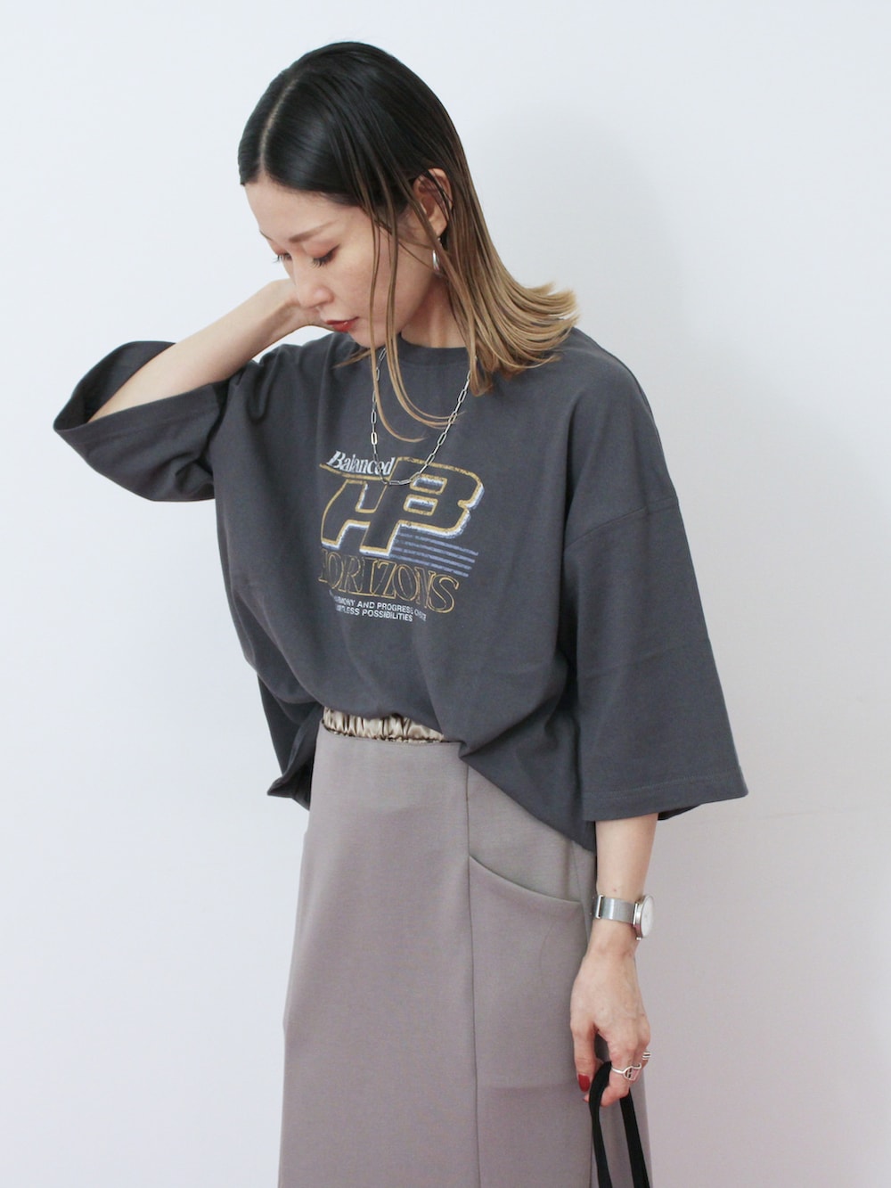 グレー系のスカート、ブラック系のハンドバッグ、ブラウン系のドレスシューズを着用したレディースの秋コーディネートの2枚目の写真