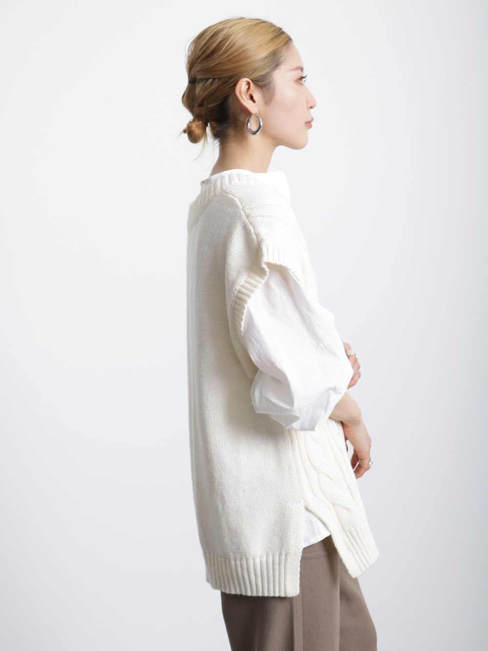 ブラウン系のブーツ、ホワイト系のニット/セーター、ホワイト系のシャツ/ブラウスを着用したレディースの冬コーディネートの2枚目の写真