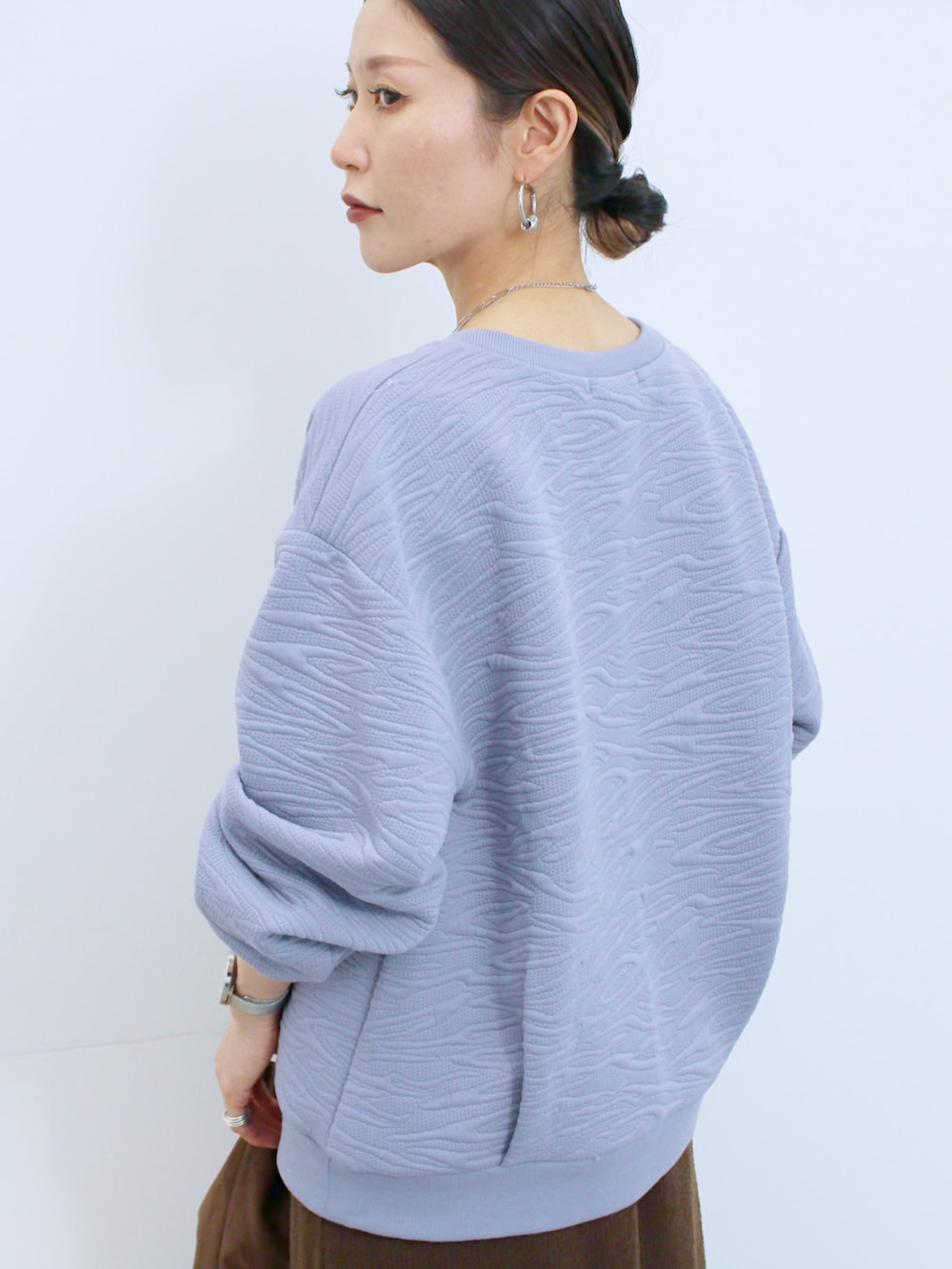 ブラウン系のスカート、ブラウン系のハンドバッグ、ベージュ系のドレスシューズを着用したレディースの冬コーディネートの3枚目の写真