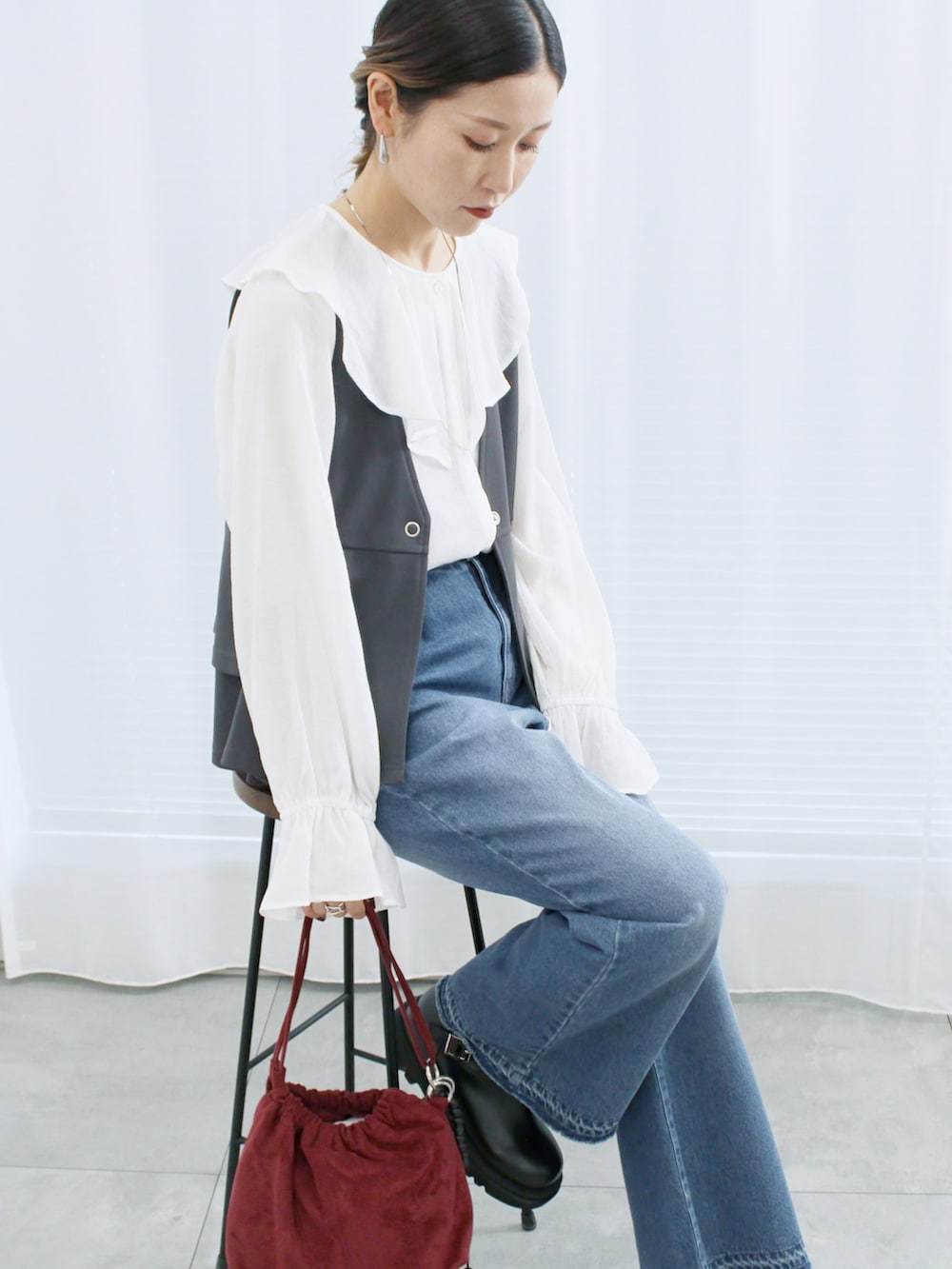 グレー系のベスト、ホワイト系のシャツ/ブラウス、ブルー系のその他パンツを着用したレディースの秋コーディネートの2枚目の写真