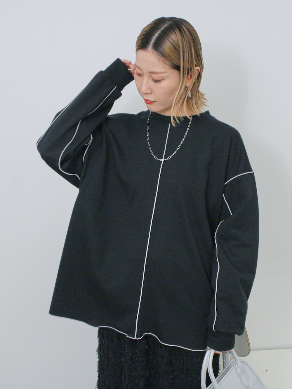 ブラック系のTシャツ/カットソー、シルバー系のハンドバッグ、ホワイト系のドレスシューズを着用したレディースの冬コーディネートの4枚目の写真