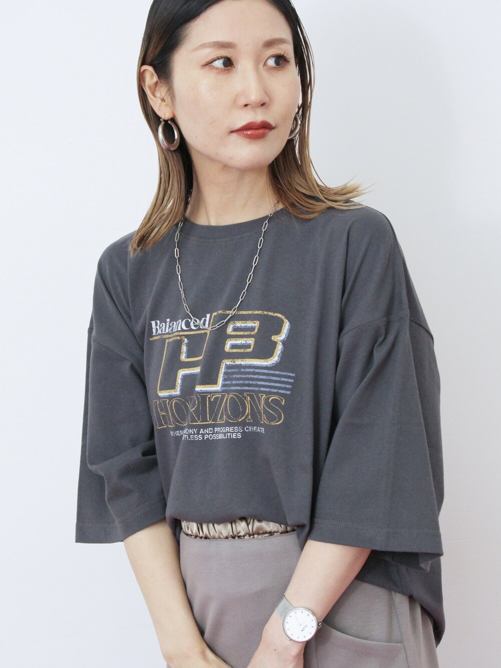 グレー系のスカート、ブラック系のハンドバッグ、ブラウン系のドレスシューズを着用したレディースの秋コーディネートの3枚目の写真