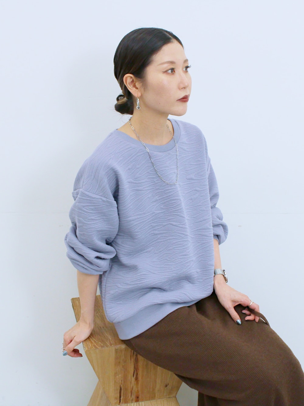 ブラウン系のスカート、ブラウン系のハンドバッグ、ベージュ系のドレスシューズを着用したレディースの冬コーディネートの2枚目の写真