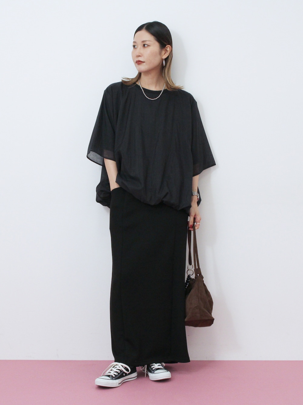 ブラック系のTシャツ/カットソー、ブラック系のスカート、ブラウン系のハンドバッグを着用したレディースの秋コーディネートの2枚目の写真