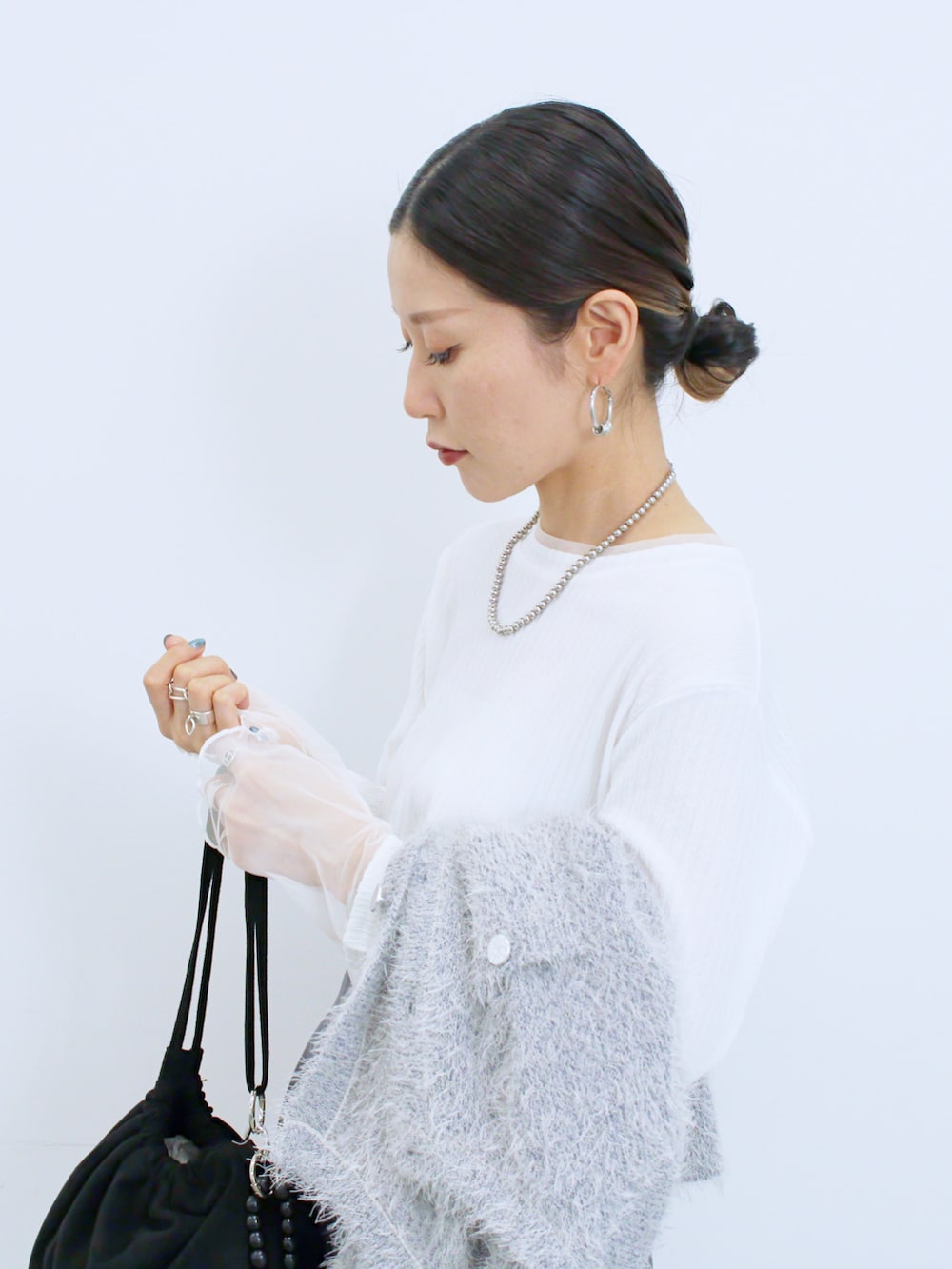 ブラック系のハンドバッグ、ブラック系のドレスシューズ、ホワイト系のTシャツ/カットソーを着用したレディースの冬コーディネートの4枚目の写真